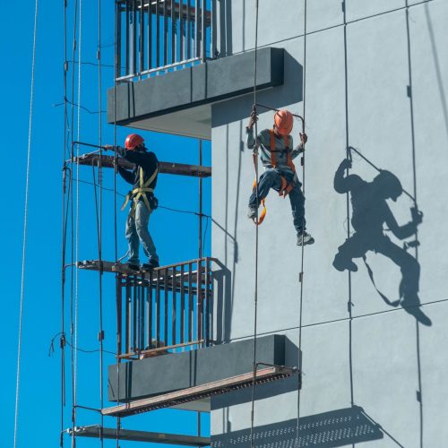 Couple of workers fixing and climbing a scaffolding while following all the safety measures A couple of workers fixing and climbing a scaffolding while following all the safety measures